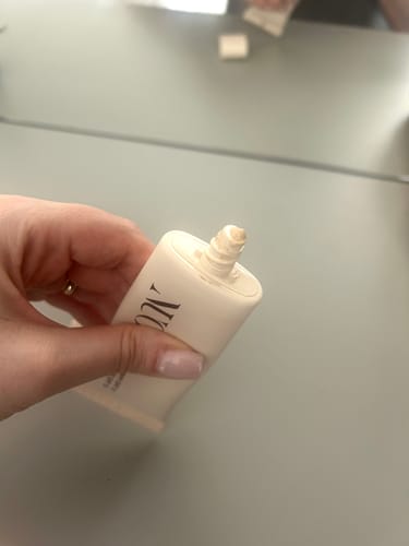 Reviewer's hand holding an open tube of BB Cream SPF30, showing the light-beige product on the nozzle.