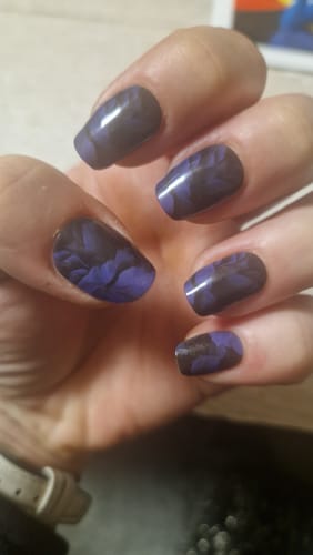 Rezensent zeigt eine Nahaufnahme seiner lila-schwarzen 'Twilight Woods' UV-Gel-Nagel-Maniküre.
