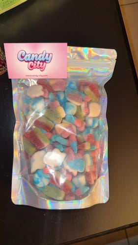 Customer's holographic bag filled with assorted colorful gummy sweets sitting on a dark table.