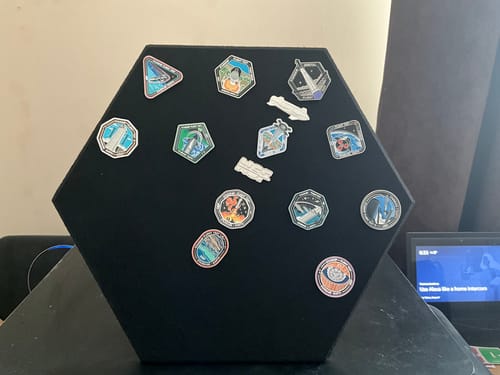 A customer's Starship Flight Pin Collection displayed on the black hexagonal mount, sitting on a desk.