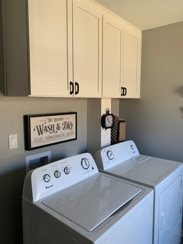 Customer's personalized laundry sign with a black floating frame hanging above a washer in a laundry room.