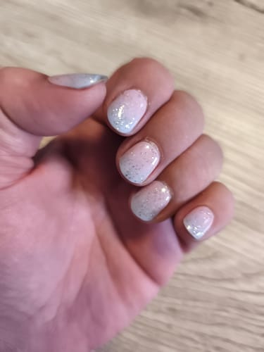 Nahaufnahme der Hand eines Rezensenten, die die 'Candy Sorbet' UV-Gel-Nagelfolien mit einem Glitzer-Decklack zeigt.