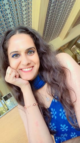 Reviewer smiling while wearing the delicate Rose Gold Harmony Bracelet on her wrist with a blue outfit.