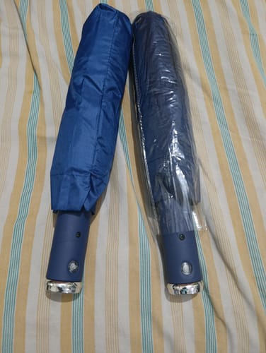 Customer's two folded UV Protected Umbrellas, one in a blue sleeve and the other in plastic wrap.