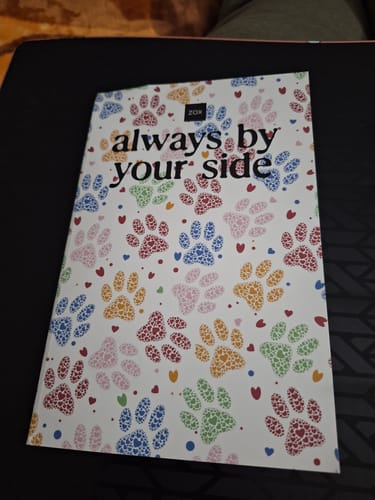 Customer's April 2026 Booklet featuring a colorful paw print cover with the text 'always by your side'.