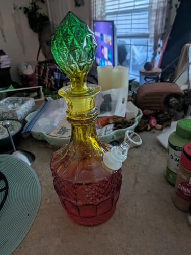 Customer's Vintage Decanter water pipe with red-to-yellow ombre glass and a faceted green stopper on a counter.