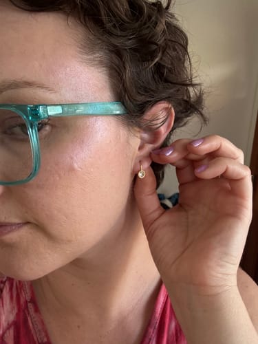 A close-up of a reviewer wearing the gold Olivia Crystal Drop Earring.