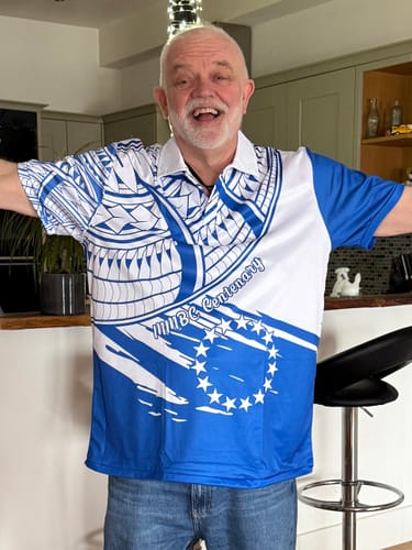 Reviewer happily wearing the custom blue and white Cook Islands polo shirt with a flag style design and centenary text.