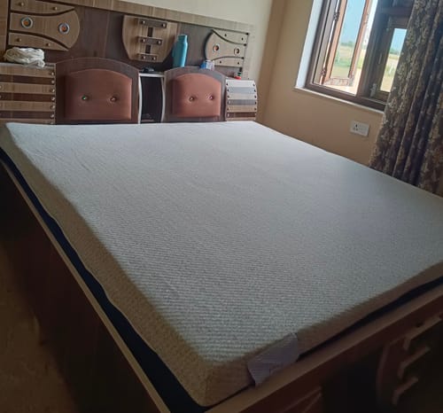 Customer's Flo Anti-Gravity™ Mattress with its textured white cover, set up on a wooden bed frame.