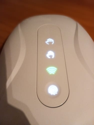 Vásárló bekapcsolt HandCare+ Regeneráló Kézmasszírozójának közeli képe, amelyen a világító kezelőfelület látható.