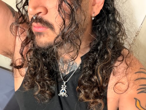 Reviewer with long curly hair wearing the REAL 6TH CIRCLE OF HELL SEPTUM in their nose.