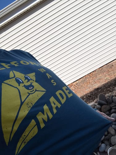 Close-up of a customer holding their blue 'An Effort Was Made Long Sleeve Tee' outdoors.