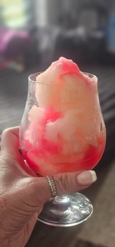 Customer holding a frosty pink and white slushie topped with Sour Puss Strawberry.