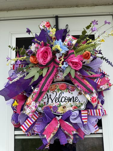 Customer's vibrant wreath on a door, made with the horizontal stripe ribbon, purple mesh, and a 'Welcome' sign.