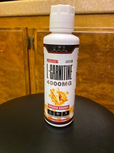 Customer's white bottle of Liquid L-Carnitine 4000MG in Berserk Banana flavor on a stool.