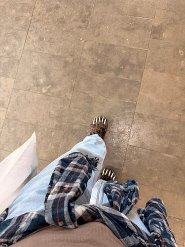 Reviewer's point-of-view shot wearing the dark leopard print Bravest Studios Bear Claw Mules on a tiled floor.