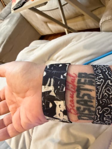 Reviewer's wrist wearing three different Mystery Club+ bracelets over a tattoo.
