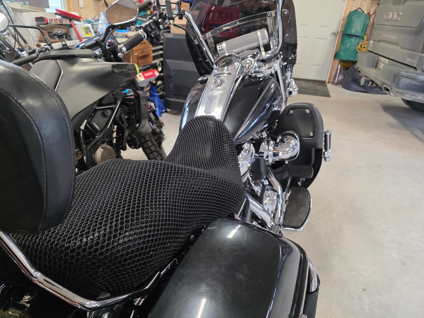 Wind Rider 3D mesh seat cover fitted over the seat of a Harley bagger, full bike visible in a shaded garage
