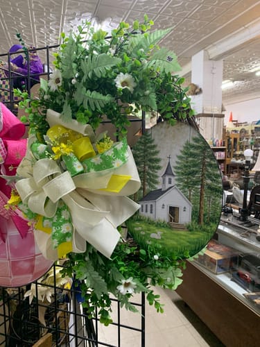 Customer's decorated Magnolia Wreath Base with added greenery, flowers, and a large multi-ribbon bow.