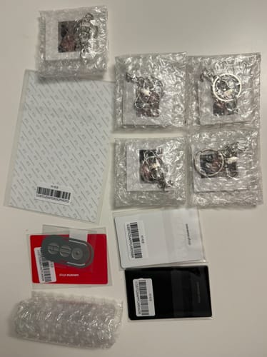 Customer displays selfie keyrings and photocards from the BTS ARIRANG 5TH ALBUM set, packaged in bubble wrap.