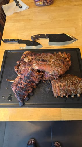 A customer's large LIXY knife, for which this PU sheath is designed, next to ribs on a cutting board.