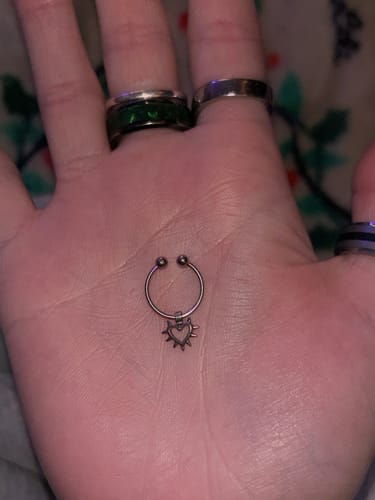 Customer holding the silver Faux Spiked Heart Septum in their open palm.