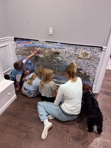 Customer and three children on the floor, pointing at details on the large WGSAD USA Edition poster.