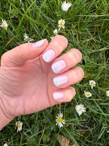 Rezensent zeigt die Candy Sorbet UV-Gel-Folien mit Ombré-Verlauf auf kurzen Nägeln über einer Wiese mit Gänseblümchen.
