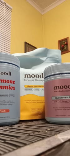Customer's Mango Passionfruit Enhanced Electrolytes pouch sitting on a table with other Moodi products.