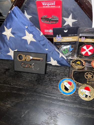 Reviewer's 10mm Wrench Keychain in its open box, displayed with a collection of memorabilia.