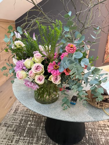 Customer's Creative Poetry flower arrangement with pink roses and lush greenery in a glass vase on a modern table.