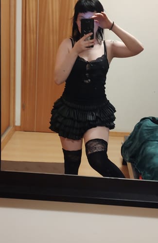 Reviewer in a mirror selfie wearing the Artemis Grunge Puffy Mini Skort with a black lace cami and thigh-high stockings.