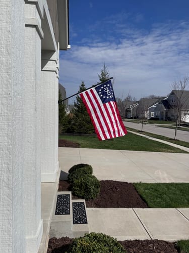 Customer's America 250 Collector's Edition Betsy Ross Flag waving on a flagpole attached to a home's front porch.