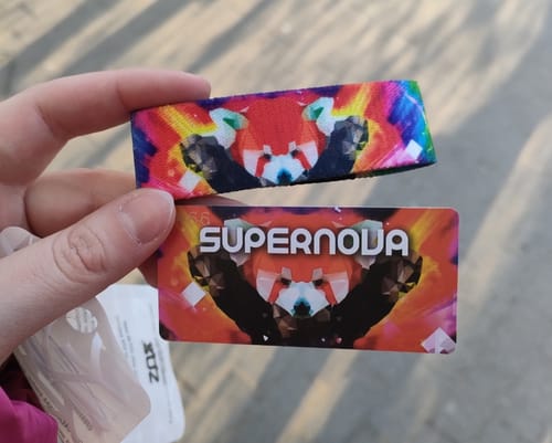 Reviewer's hand holding the colorful Supernova Bracelet and its matching card with a red panda design.