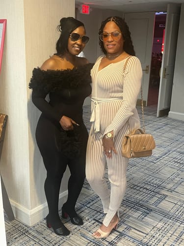Customer wearing the black Naked Off-Shoulder Roses Jumpsuit, standing with a friend at an event.