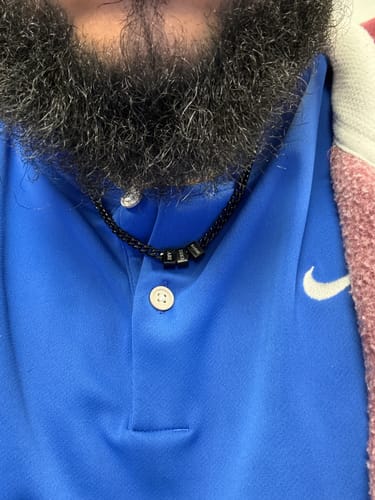 Customer wearing the black Legacy necklace with several small beads over a blue polo shirt.