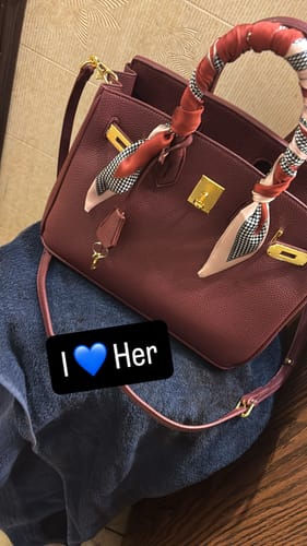 Customer's Warkin Bag in Wine with a patterned scarf on the handle, resting on their lap.