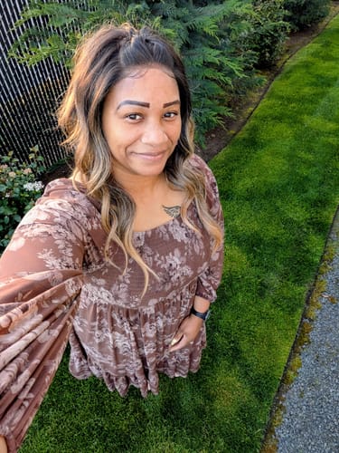 Reviewer wearing the wavy, honey-blonde Outre Perfect Hairline wig styled in a half-up ponytail outdoors.