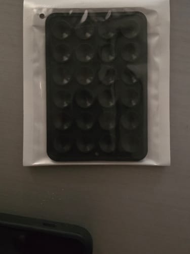 Customer's black StickyPod with suction cups, shown inside its clear plastic packaging.