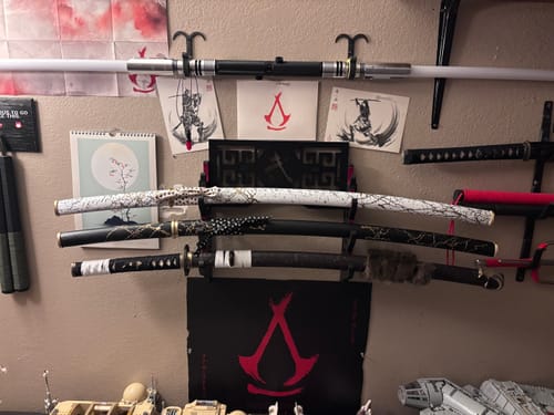 Customer's black and white Ghost of Yōtei Dawn katanas mounted on a wall rack as part of a collection.