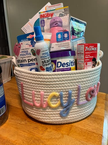 Customer's personalized knitted basket with 'LUCYLOU' in multicolor yarn, used as a baby shower gift basket.