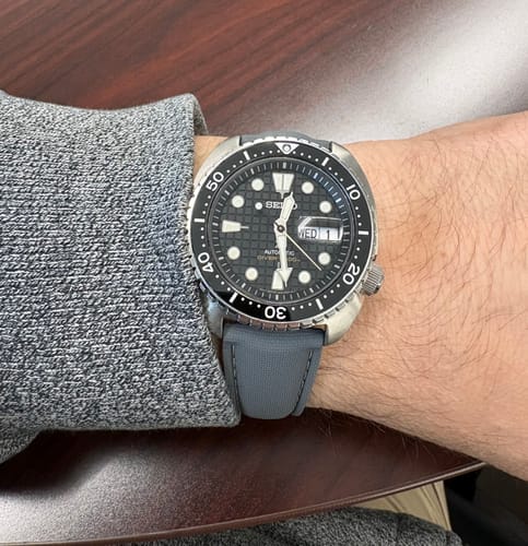 Reviewer's wrist wearing a dive watch with the gray Sailcloth Rubber Deploy strap.