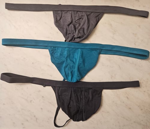Reviewer's 3-pack of Modal thongs in grey, cyan, and black laid flat on a surface.