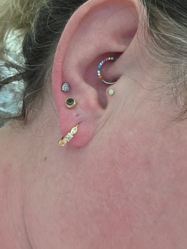 Customer wearing the gold Shapeshifter huggies in their earlobe as part of a stacked earring look.