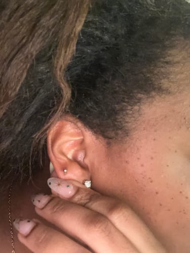 Close-up of a reviewer wearing the small, gold Polished Ball Stud in their second ear piercing.