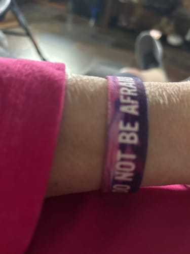 Reviewer wearing a purple and pink bracelet on their wrist with the text 'DO NOT BE AFRAID'.