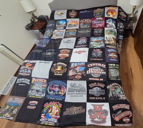 Customer's large Project Repat T-Shirt Quilt, made of many motorcycle-themed shirts, spread across a bed.