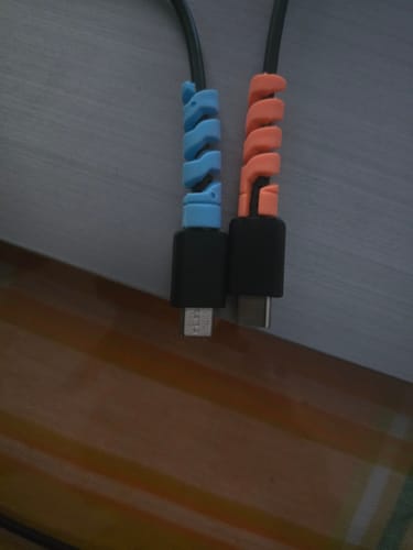 Close-up: Reviewer's blue and orange cable protectors from the set, installed on two different charging cables.