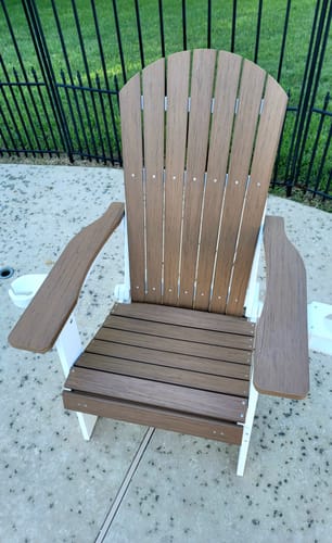 Customer's two-tone brown and white Folding Adirondack Chair on a patio with the footrest closed.