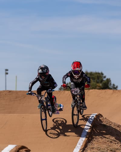 Customer photo of two young BMX racers in mid-air competing on a dirt track.